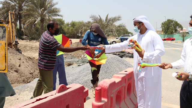 صورة بعنوان: "أولياء أمور دبا الحصن" يوزع قبعات مظلية على العمال  