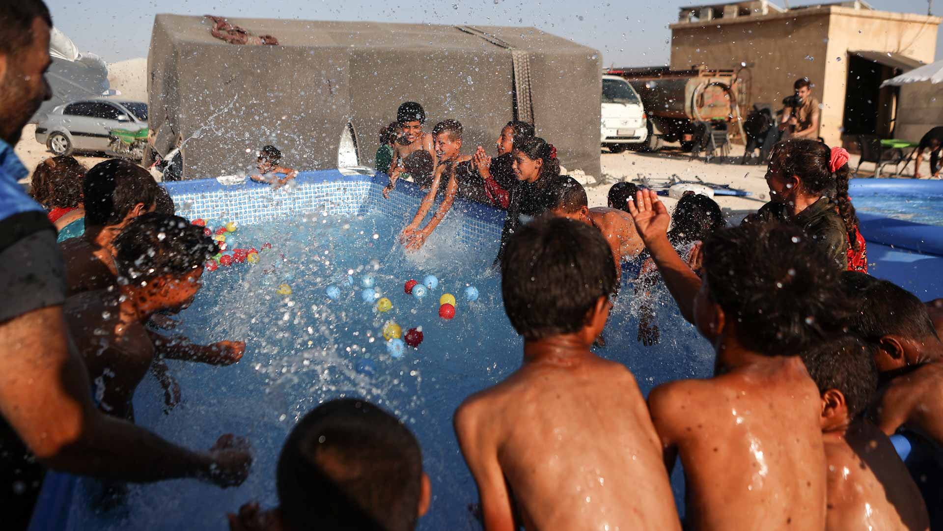 Image for the title: Mobile pools offer relief from heat to chldn. in north Syria camps 