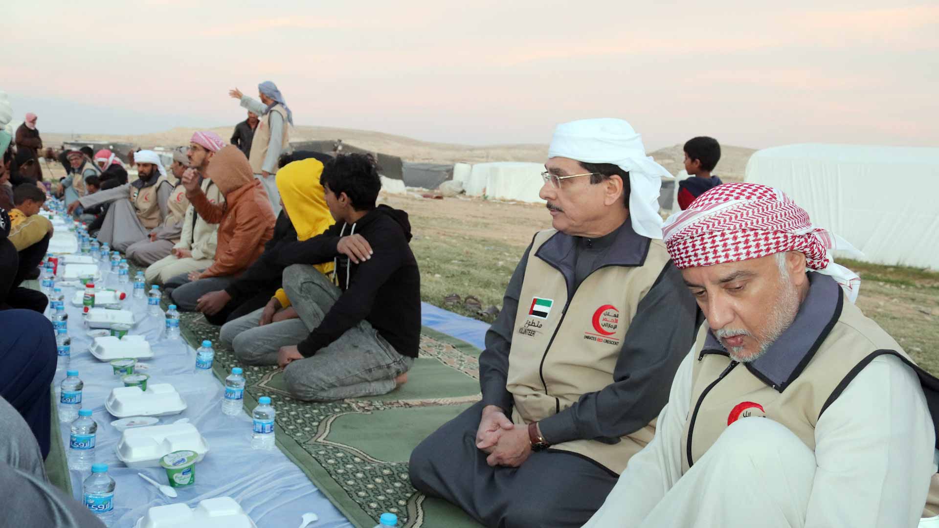 صورة بعنوان: الهلال الأحمر ينفذ إفطار صائم لسكان خيم قرب مخيم الإماراتي الأردني 