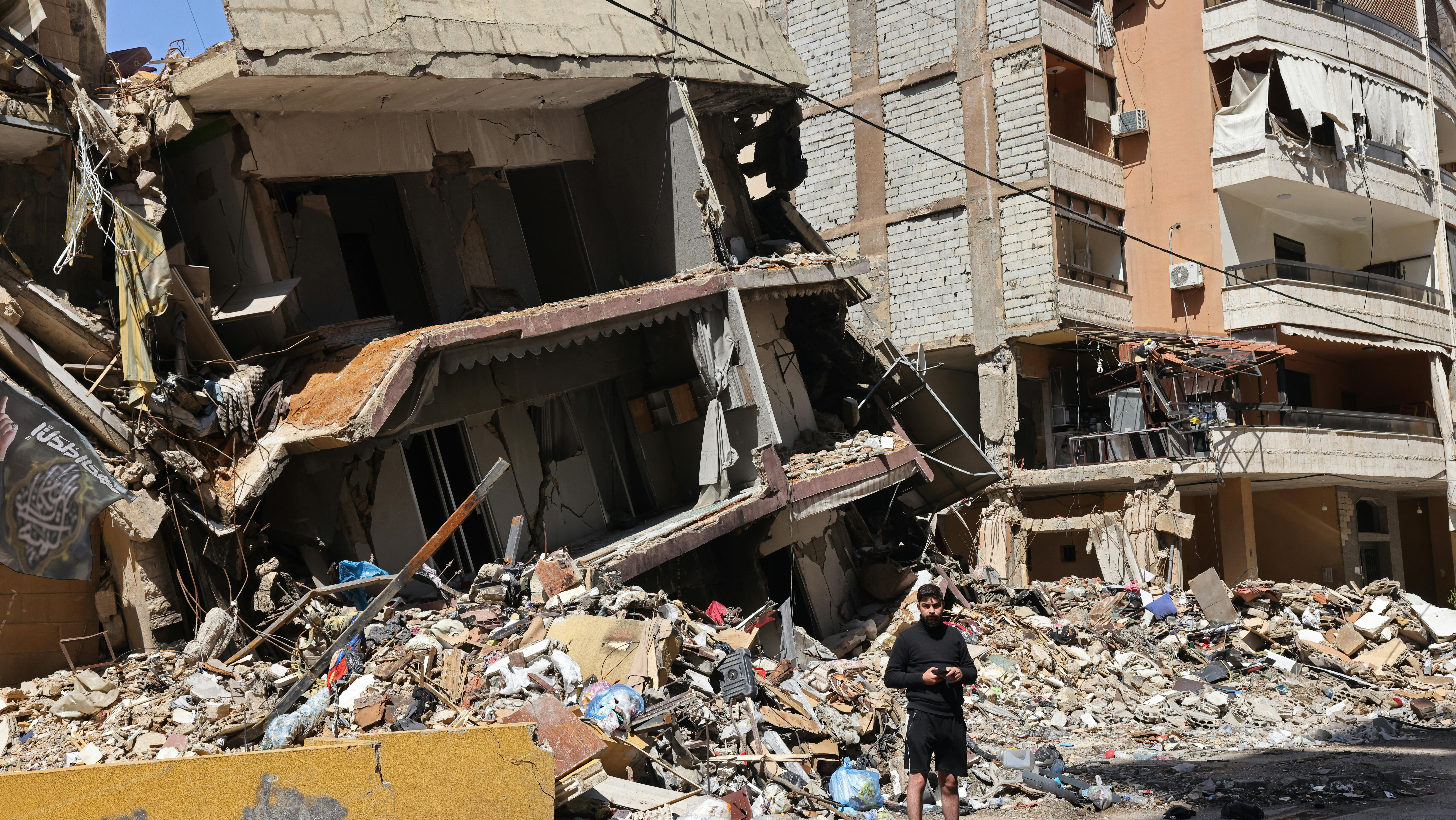 لبناني يقف وسط أنقاض مبنى مُدمّر في الضاحية الجنوبية لبيروت بعد غارة إسرائيلية